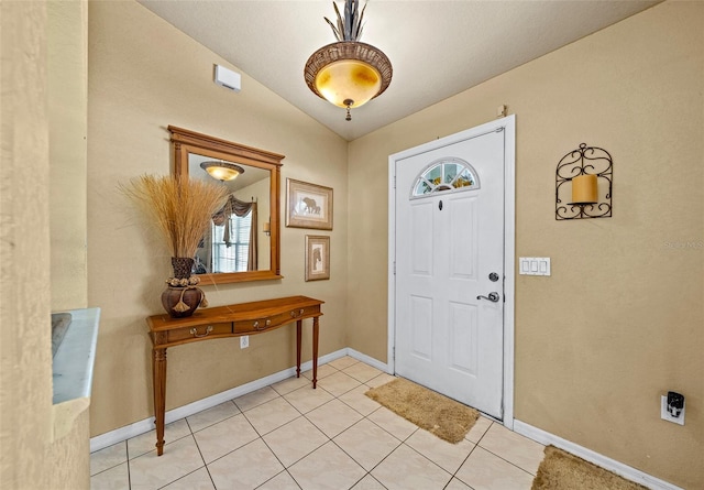 foyer entrance featuring light tile patterned floors, baseboards, and vaulted ceiling