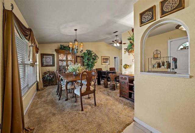 carpeted dining space featuring lofted ceiling and ceiling fan with notable chandelier