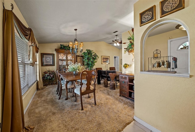 carpeted dining room featuring lofted ceiling, ceiling fan with notable chandelier, and baseboards