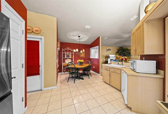 kitchen featuring an inviting chandelier, light brown cabinetry, white appliances, and hanging light fixtures