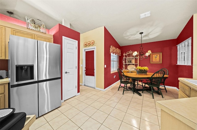 interior space featuring hanging light fixtures, lofted ceiling, an inviting chandelier, stainless steel fridge, and light tile patterned flooring