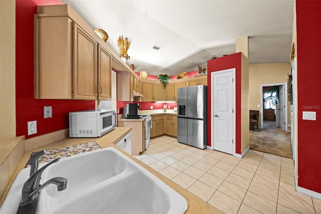 kitchen with electric range oven, vaulted ceiling, light tile patterned floors, sink, and stainless steel fridge