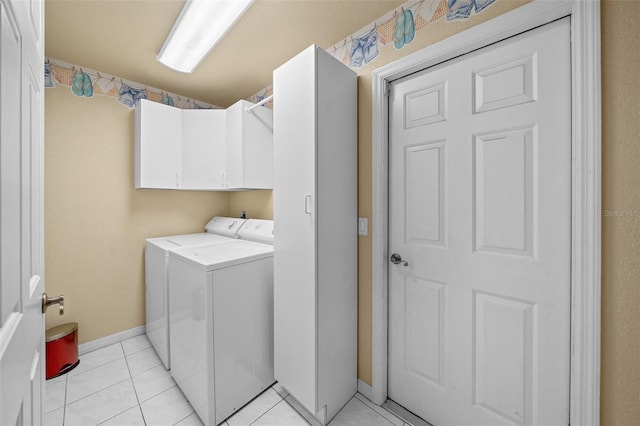 laundry area featuring separate washer and dryer, light tile patterned flooring, cabinet space, and baseboards