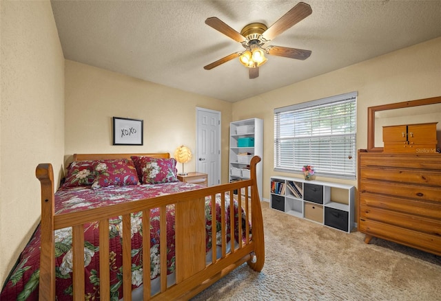 bedroom with ceiling fan, carpet flooring, and a textured ceiling