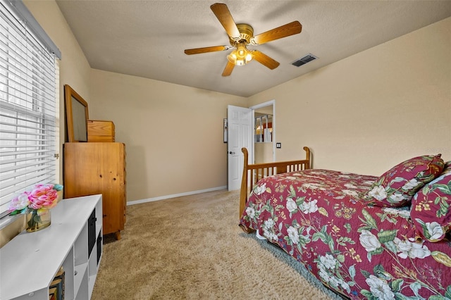 bedroom featuring light carpet, baseboards, visible vents, and a textured ceiling