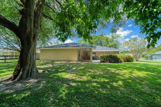 rear view of property with a patio, a lawn, a fenced backyard, and stucco siding