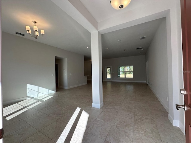 tiled empty room with a notable chandelier