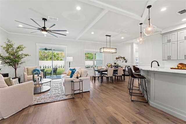 living room featuring beam ceiling, ceiling fan, crown molding, and hardwood / wood-style floors