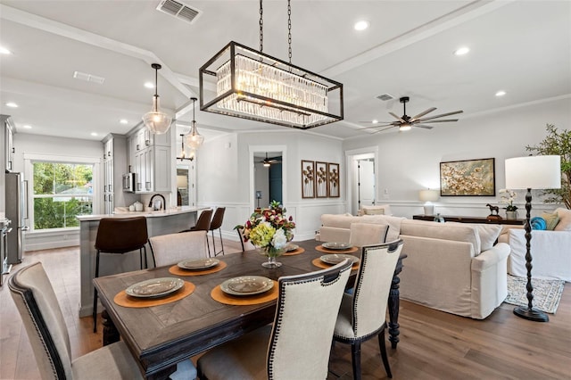 dining room featuring hardwood / wood-style floors, ceiling fan with notable chandelier, and sink