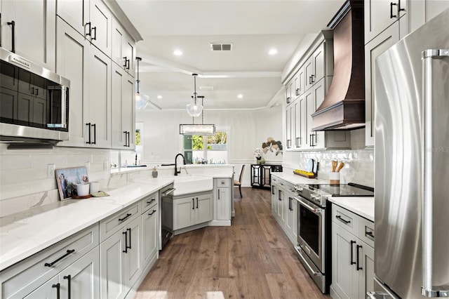 kitchen featuring appliances with stainless steel finishes, premium range hood, ornamental molding, dark wood-type flooring, and decorative light fixtures