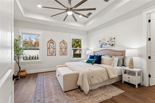 bedroom with a raised ceiling, ceiling fan, and dark hardwood / wood-style flooring