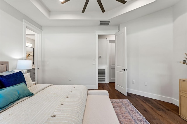 bedroom featuring ceiling fan, dark hardwood / wood-style flooring, and a tray ceiling