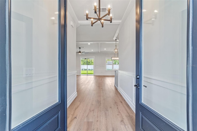 foyer entrance with ceiling fan with notable chandelier and light wood-type flooring