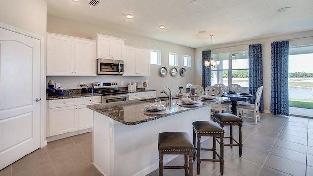 kitchen with a center island with sink, light tile patterned floors, appliances with stainless steel finishes, and sink