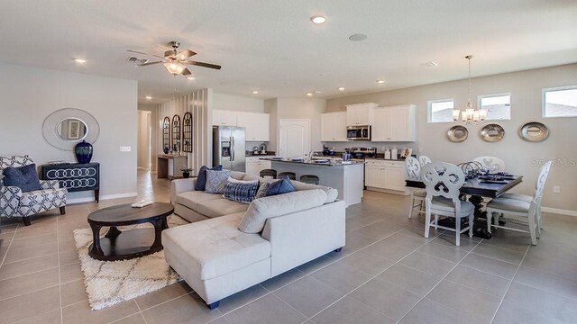 tiled living room featuring ceiling fan with notable chandelier