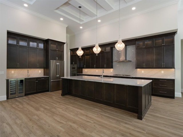 kitchen with appliances with stainless steel finishes, beam ceiling, wall chimney range hood, and light hardwood / wood-style flooring