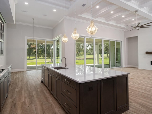 kitchen with dark brown cabinets, beam ceiling, ceiling fan with notable chandelier, light wood-style floors, and a sink