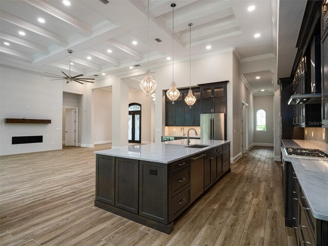 kitchen with light hardwood / wood-style floors, high end refrigerator, a large island, coffered ceiling, and sink