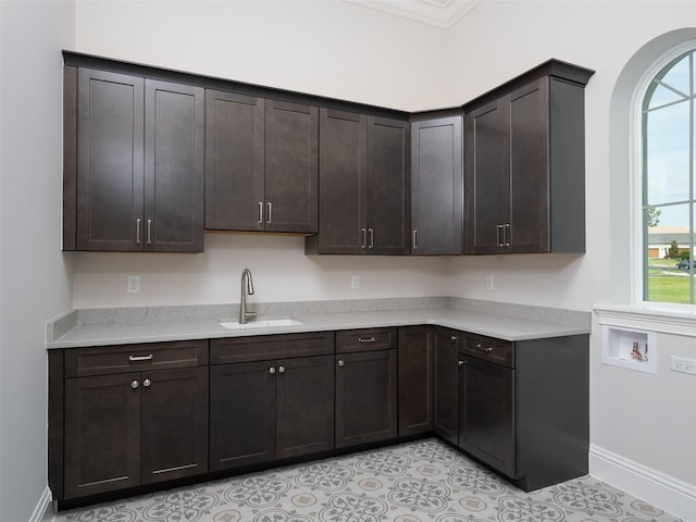 kitchen featuring a sink, dark brown cabinets, light tile patterned floors, and light countertops