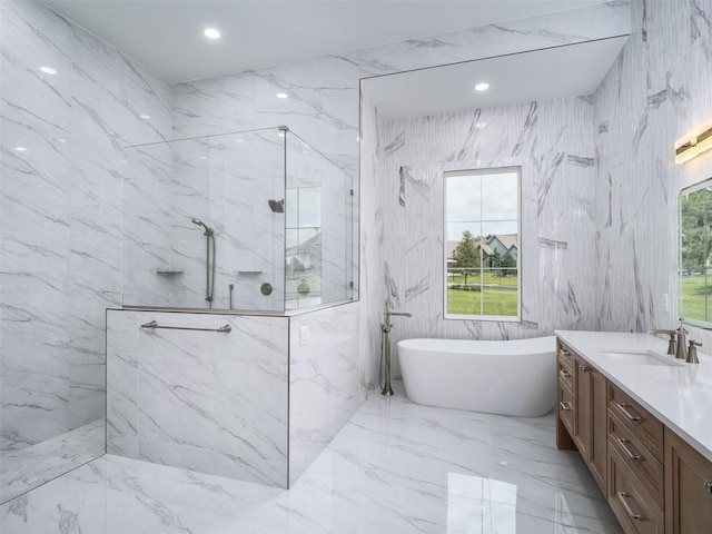full bath featuring vanity, stone wall, a freestanding tub, and a marble finish shower
