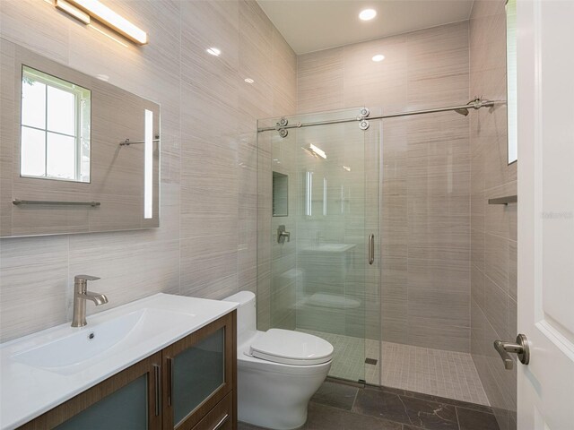 bathroom with vanity, tile patterned floors, tile walls, toilet, and walk in shower