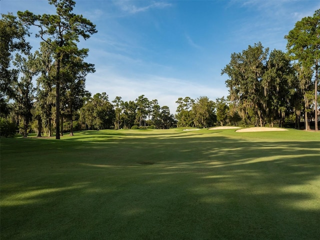 view of home's community featuring view of golf course and a yard