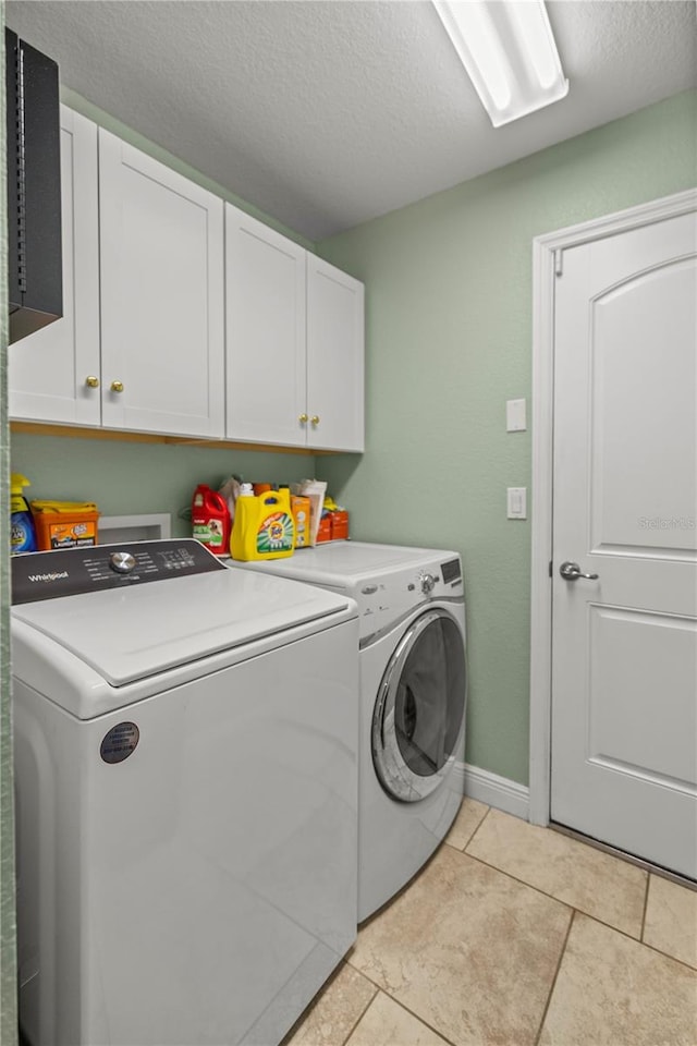 laundry room featuring washing machine and clothes dryer, light tile patterned floors, cabinets, and a textured ceiling