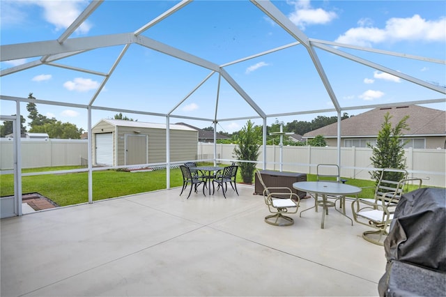 view of patio / terrace featuring glass enclosure, area for grilling, and a storage shed