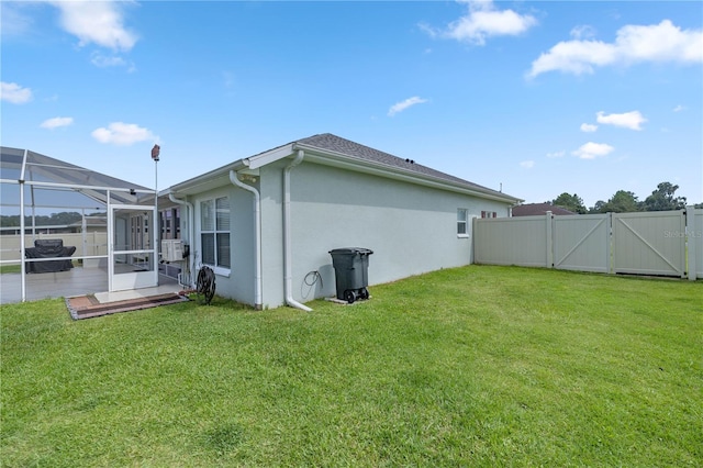 rear view of house with a lawn and a lanai