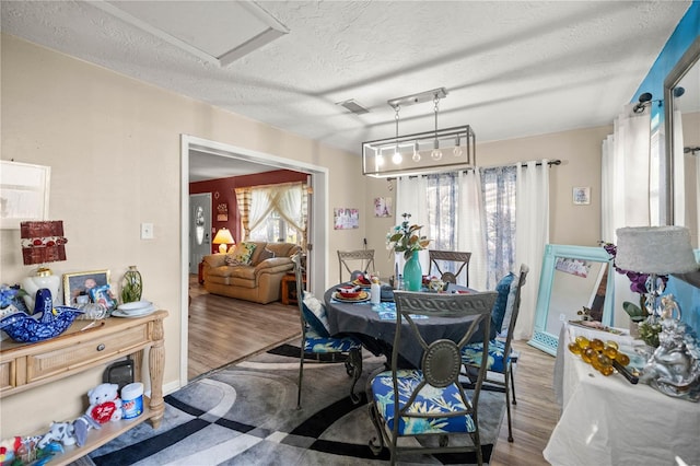 dining space with light hardwood / wood-style flooring and a textured ceiling