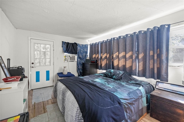 bedroom with cooling unit, light hardwood / wood-style flooring, and a textured ceiling