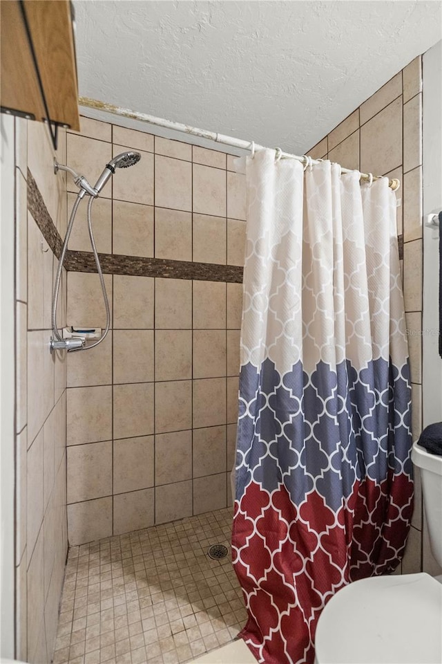 bathroom with toilet, curtained shower, and a textured ceiling