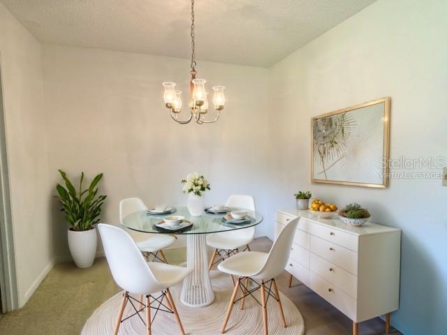 dining room with an inviting chandelier, carpet flooring, and a textured ceiling