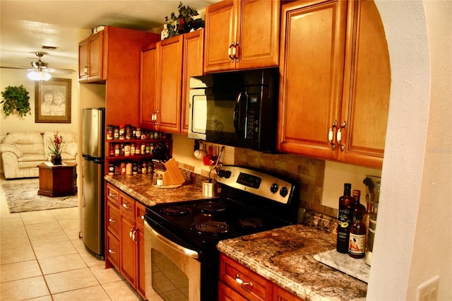 kitchen with light tile patterned floors, stainless steel appliances, light stone counters, ceiling fan, and decorative backsplash