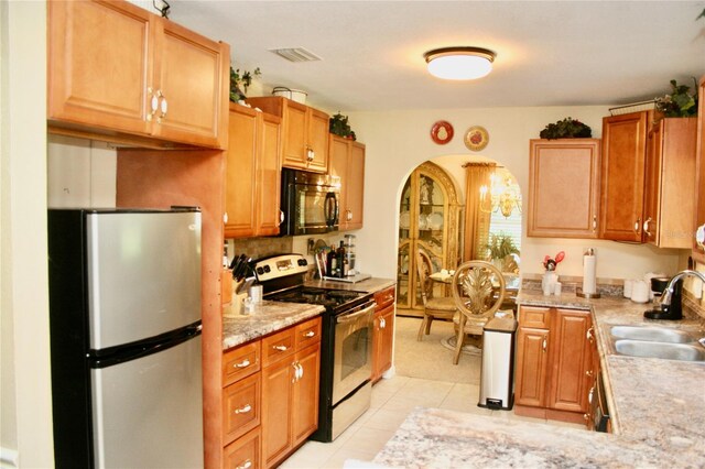 kitchen with decorative backsplash, stainless steel refrigerator, light tile patterned floors, sink, and range with electric stovetop