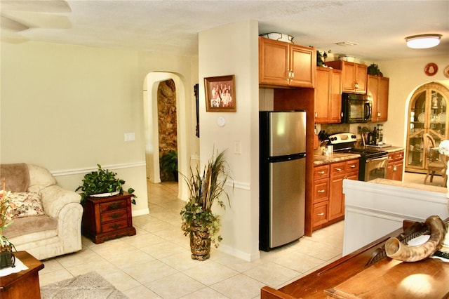 kitchen featuring stainless steel appliances, light tile patterned floors, and decorative backsplash