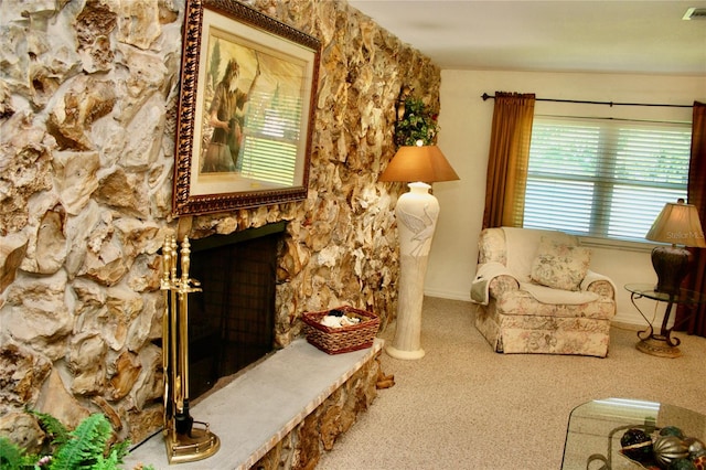 carpeted living room with a stone fireplace