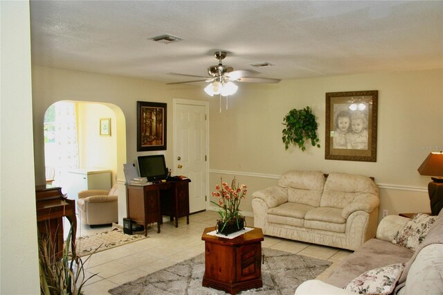 tiled living room with ceiling fan and a textured ceiling