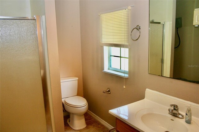 bathroom with an enclosed shower, toilet, vanity, and tile patterned flooring