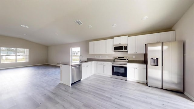 kitchen featuring white cabinets, sink, vaulted ceiling, appliances with stainless steel finishes, and kitchen peninsula