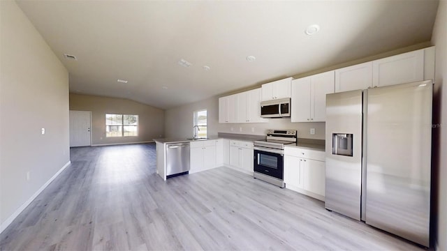 kitchen featuring light hardwood / wood-style flooring, kitchen peninsula, vaulted ceiling, white cabinets, and appliances with stainless steel finishes