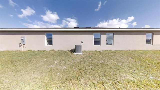 rear view of property featuring a lawn and central air condition unit