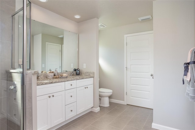 bathroom with tile patterned floors, double vanity, a shower with door, and toilet