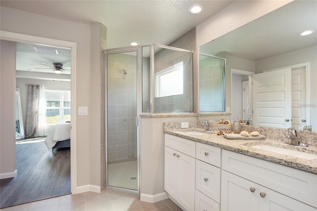 bathroom with tile patterned floors, a textured ceiling, dual bowl vanity, ceiling fan, and walk in shower