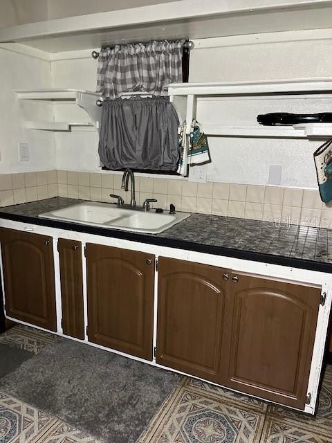 kitchen with dark brown cabinetry, backsplash, and sink