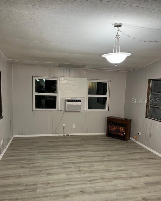 unfurnished living room featuring light wood-type flooring, cooling unit, and ornamental molding