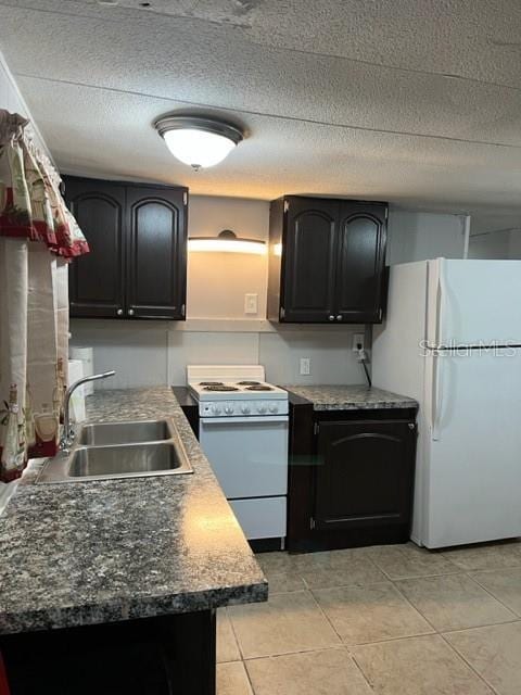 kitchen with a textured ceiling, sink, light tile patterned floors, and white appliances