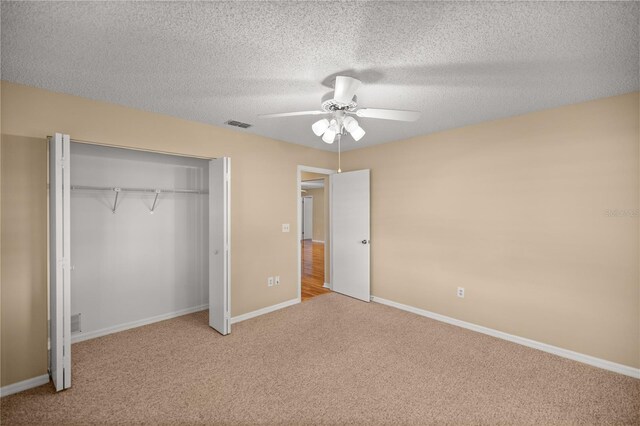 unfurnished bedroom featuring ceiling fan, light carpet, a closet, and a textured ceiling