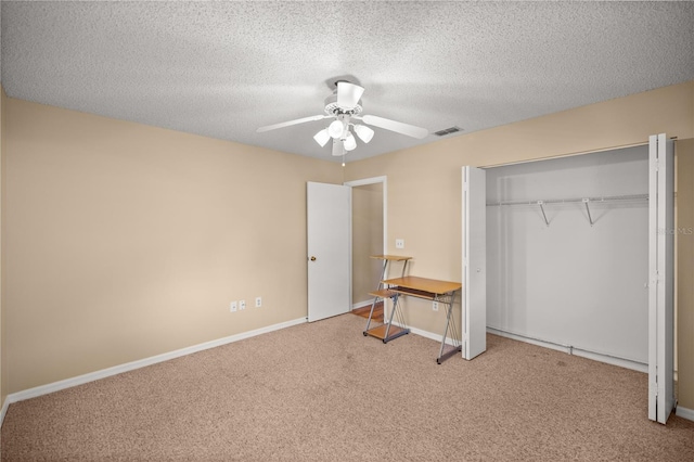 unfurnished bedroom featuring ceiling fan, light colored carpet, a closet, and a textured ceiling