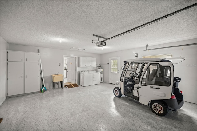 garage featuring sink, washing machine and clothes dryer, a garage door opener, and electric water heater